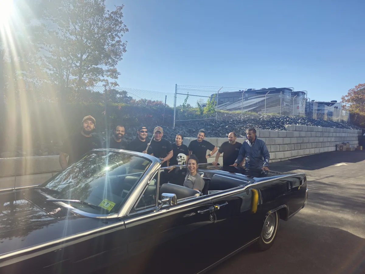 The Angels Touch crew posed behind a black classic convertible