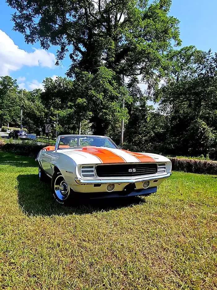 Restored Camaro RS convertible with orange stripes on the grass