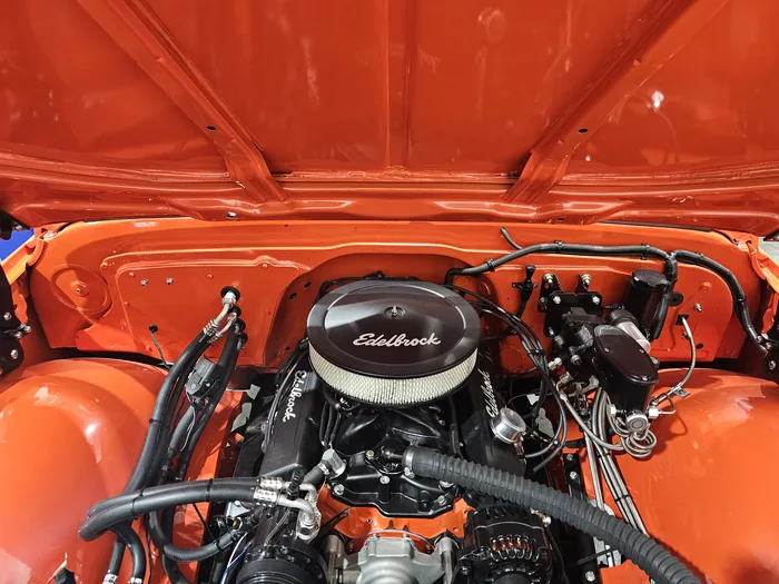Freshly built engine bay with orange paint and a chrome air cleaner