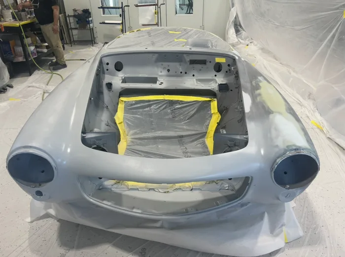 Classic car body in gray primer inside the paint shop