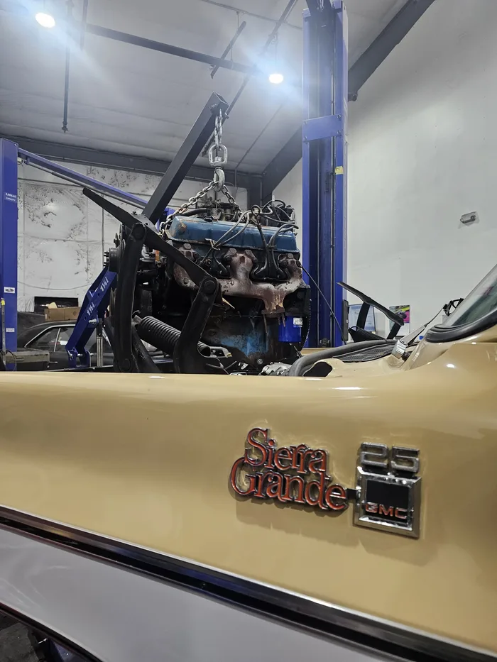 Engine on a lift beside a Sierra Grande truck in the shop