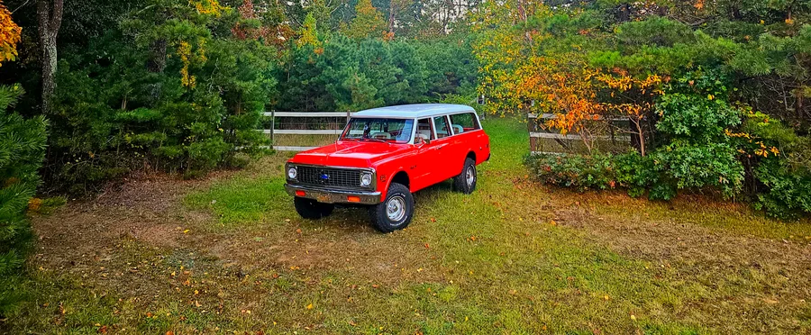 Restored red Chevrolet Suburban parked in a grassy field