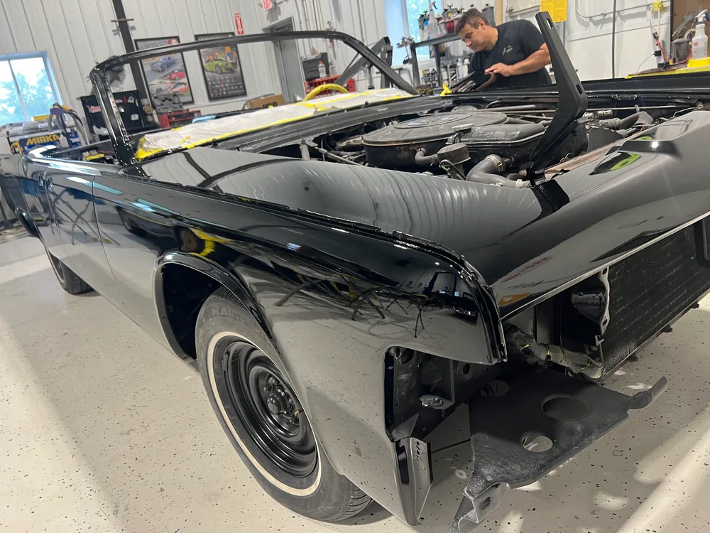 Black classic convertible with its body off the frame during a restoration